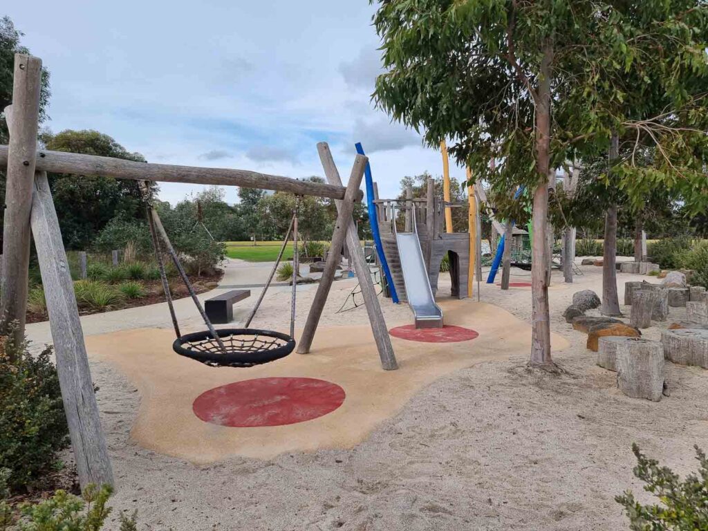 Playground equipment with swing and slide between wooden posts at warralily boulevard playground geelong
